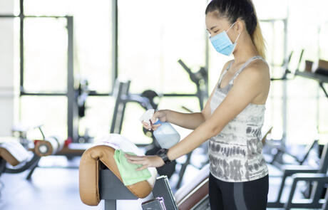 Sales and marketing woman wearing mask cleaning gym equipment Freepik stock column