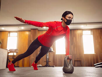 FP sport girl mask from coronavirus doing kettlebells planking listing